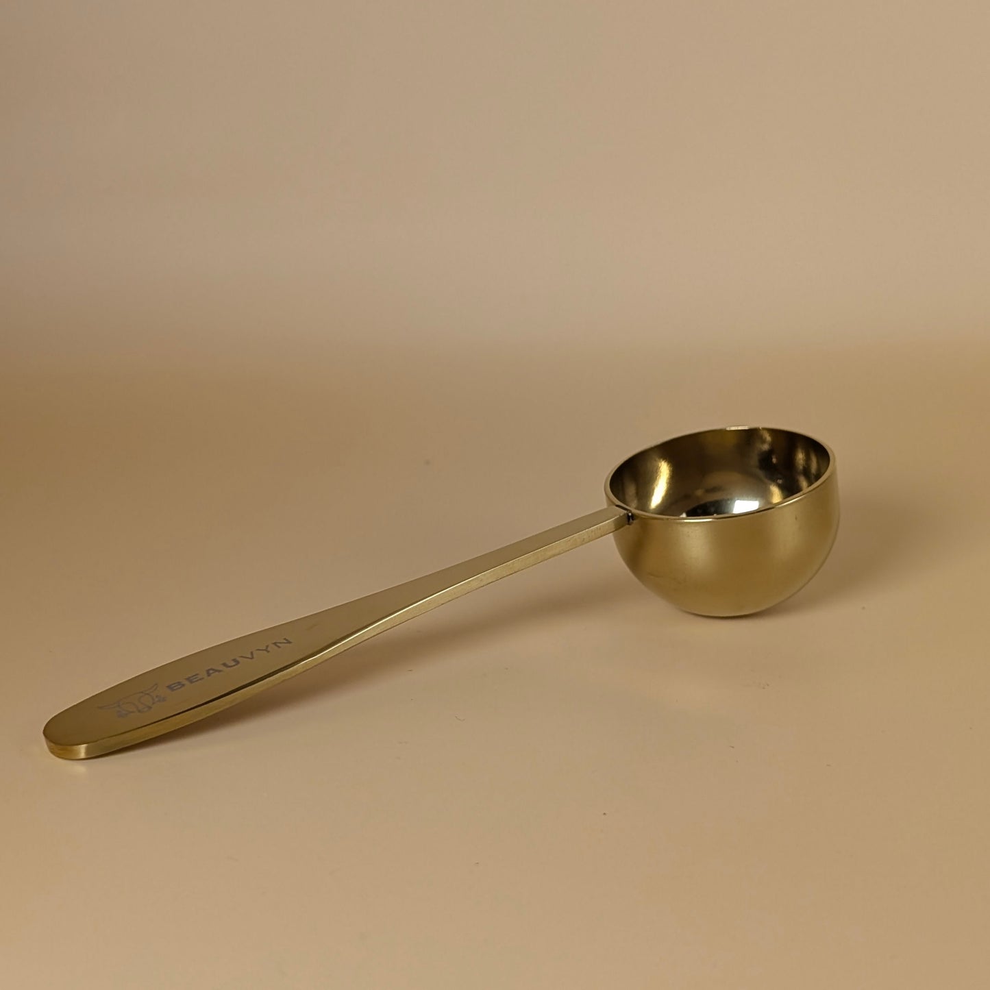 Gold measuring spoon on a beige background